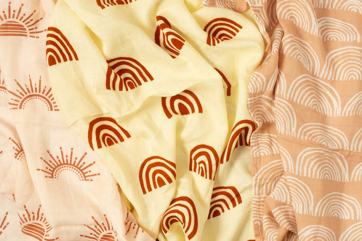 Close-up of sun and rainbow bamboo muslin cloths draped to show the print and soft gauze texture